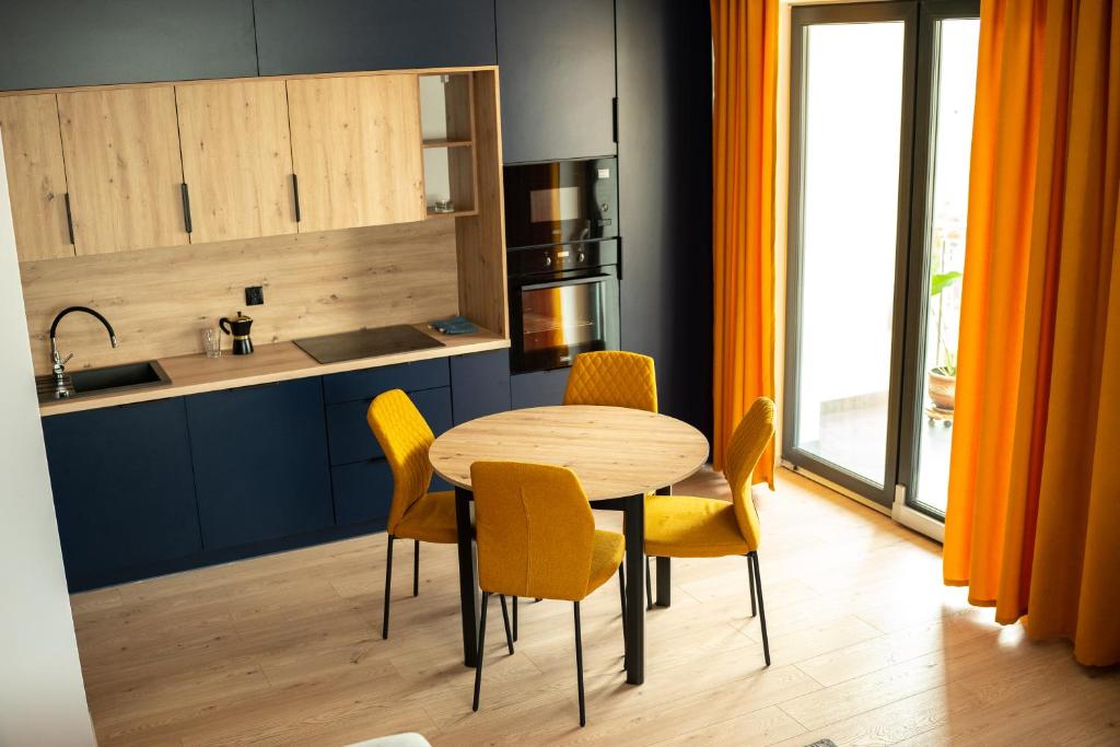 eine Küche mit einem Holztisch und gelben Stühlen in der Unterkunft Apartamenty Lesko 23 in Lesko
