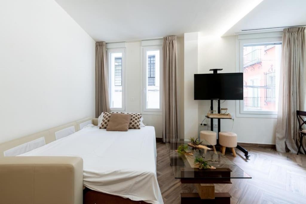 sypialnia z dużym białym łóżkiem i oknami w obiekcie Murillo Fantastic apartment downtown Sevilla w Sewilli