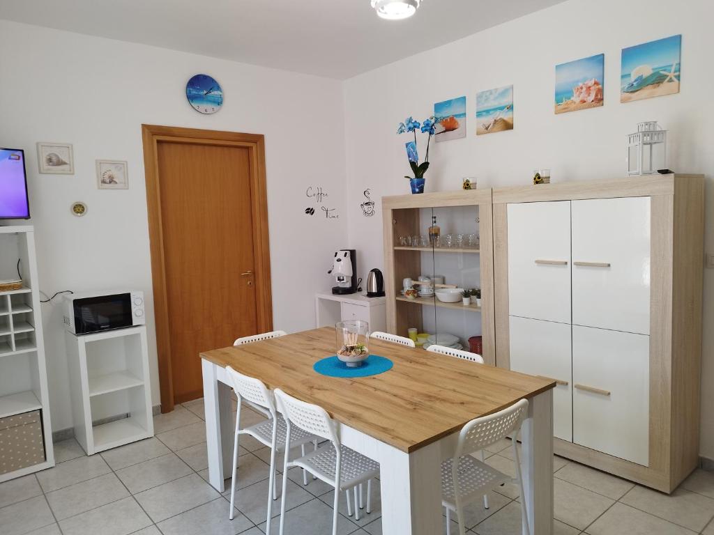 a kitchen with a wooden table and white cabinets at Casa vacanze Il sorriso di Emi in Torre Suda