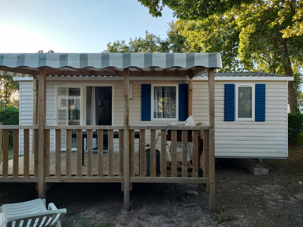 a tiny house with a porch and a roof at Mobil home Menanteau in Les Mathes