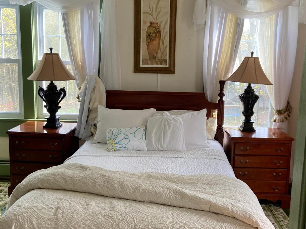 a bedroom with a large bed with two lamps and windows at Elegantly English Catskills in Liberty