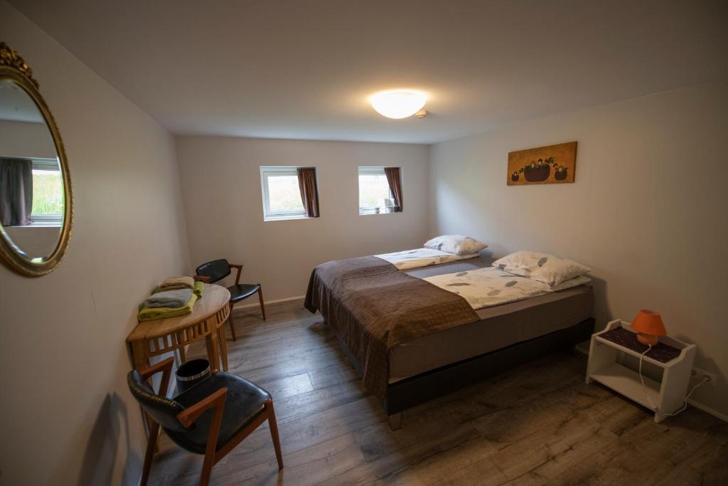 1 dormitorio con cama, mesa y espejo en Húnaver Guesthouse en Blönduós