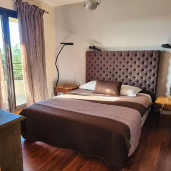 une chambre avec un grand lit avec une grande fenêtre dans l'établissement La chambre d'Aphrodite avec jacuzzi vue mer, à Porto-Vecchio