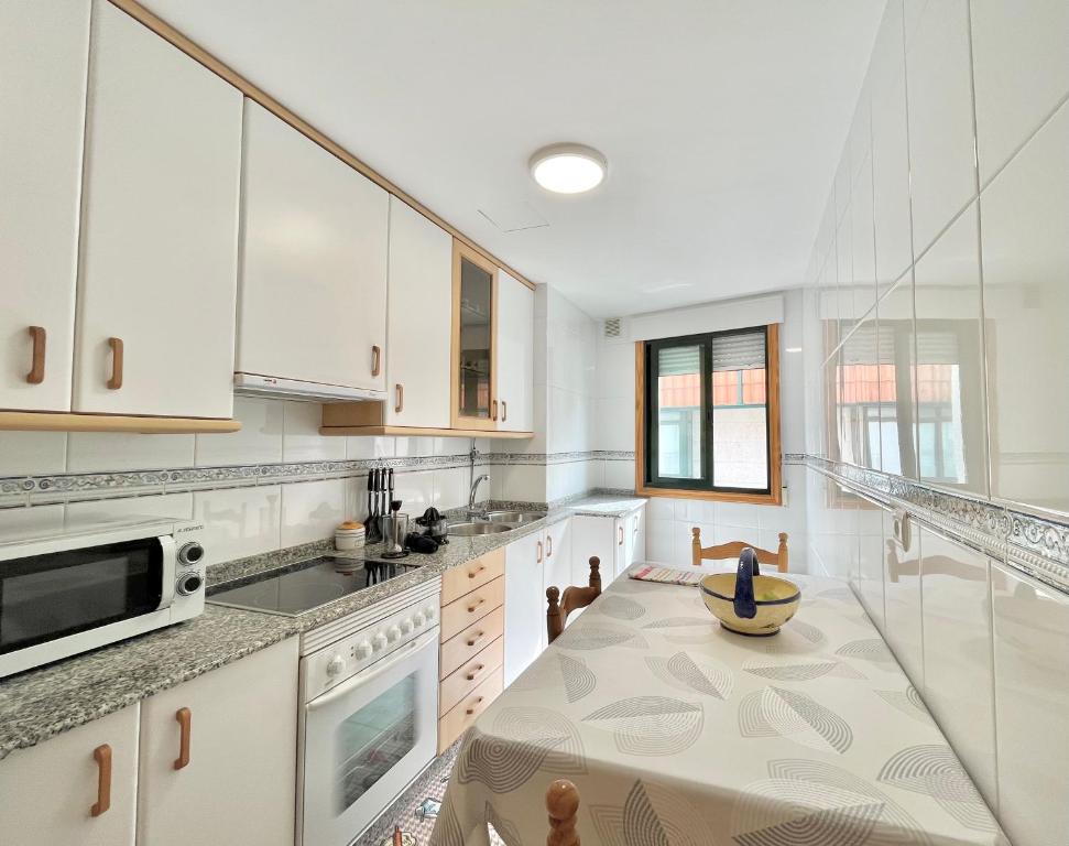 een keuken met witte kasten en een tafel met een kom erop bij Apartamento Bellavista in Portonovo