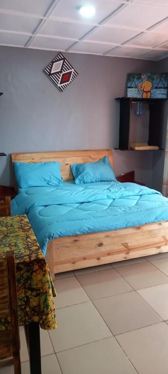 Un dormitorio con una cama con sábanas azules y una mesa. en Tommy's Budget Rooms en Kigali