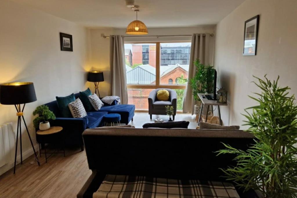 a living room with a blue couch and a large window at Modern apartment, sleeps 6, Belfast city centre in Belfast