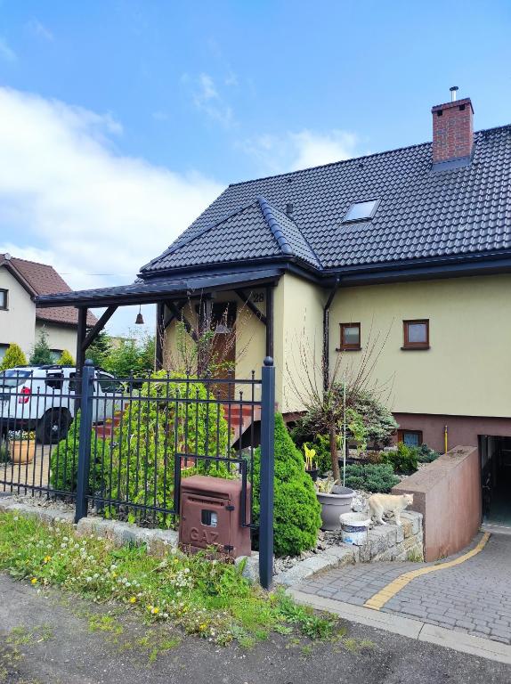 a house with a black roof and a fence at Przyjazny Domek in Tarnowskie Góry