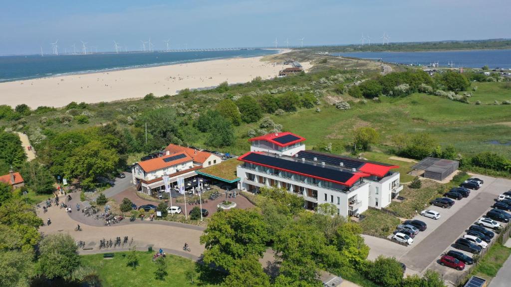 een luchtzicht op een gebouw naast een strand bij Strandhotel Duinoord in Vrouwenpolder