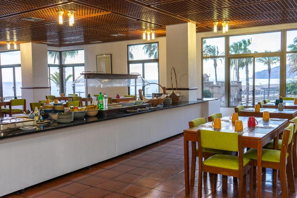 リベイラ・ブラーヴァにあるFlag Hotel Madeira - Ribeira Bravaのテーブルと椅子のあるレストラン、ビュッフェ