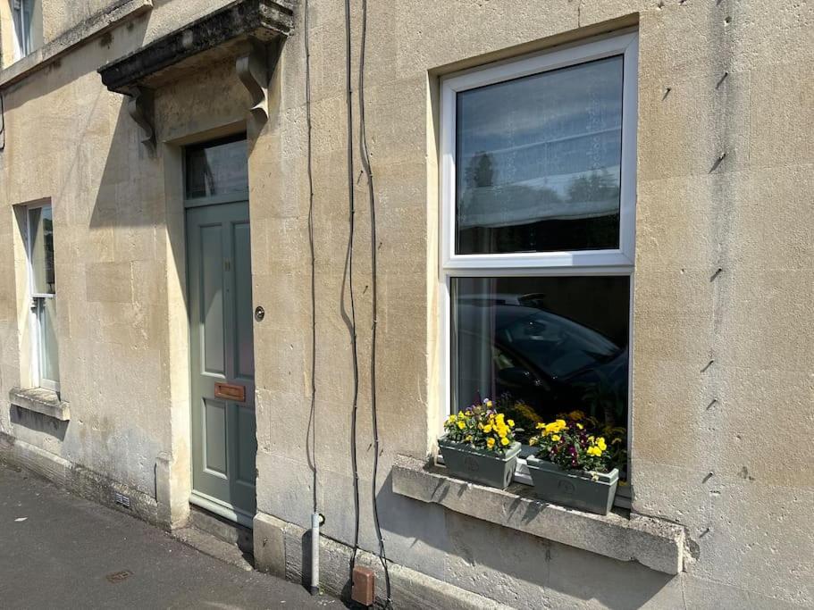 a window of a building with flowers in a window sill at Cosy 19th century two bedroomed home with continental Breakfast in Bath