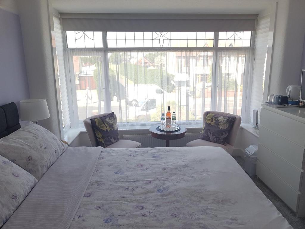 a bedroom with a bed and two chairs and a window at B&B No. 70 in Southport