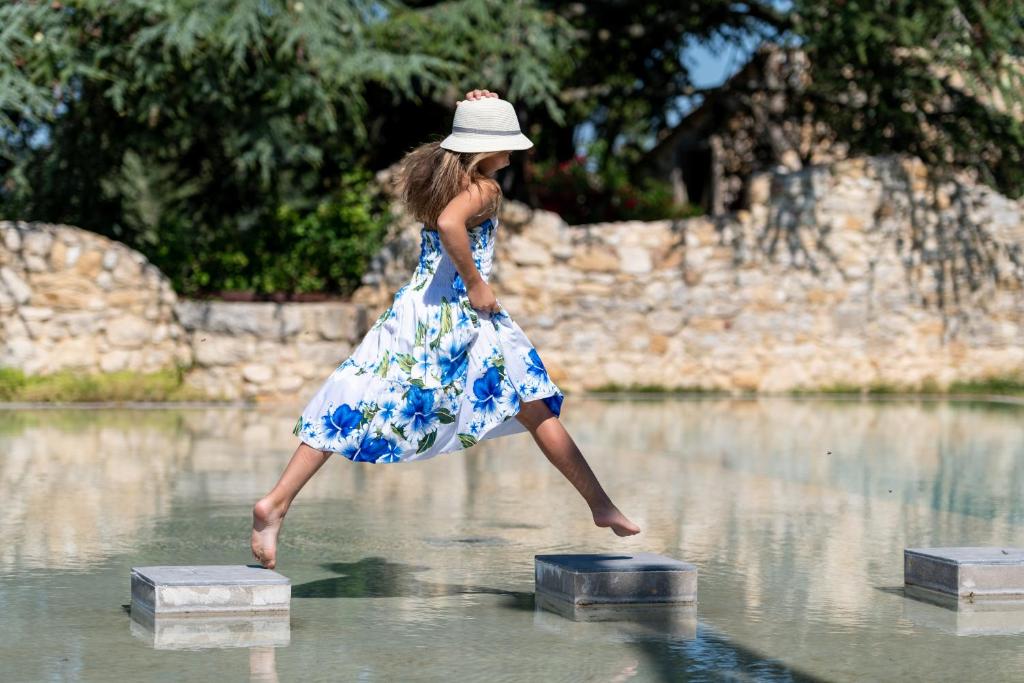 a woman in a dress jumping in the water at Domaine de Gressac in Verfeuil