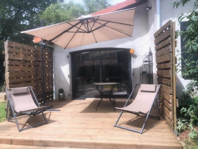 eine Terrasse mit 2 Stühlen, einem Tisch und einem Sonnenschirm in der Unterkunft Le paradis des ouches in Aubigny
