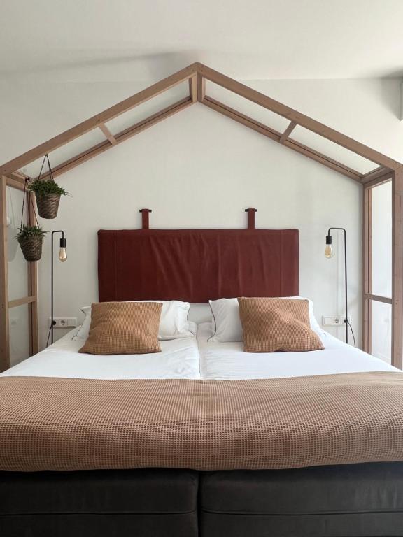 een slaapkamer met een groot bed met een houten hoofdeinde bij B&B Bij tante Teun in Naaldwijk
