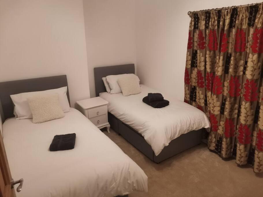 2 łóżka pojedyncze w pokoju z zasłonami w obiekcie Hopefield w mieście Newport