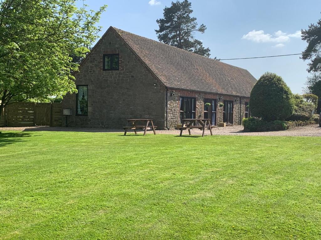 two picnic tables in front of a stone building at Upper Home Farm in Plaish