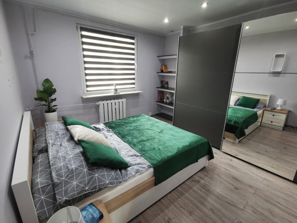 a bedroom with a large bed with a green blanket at Apartament Królowej Jadwigi in Iława