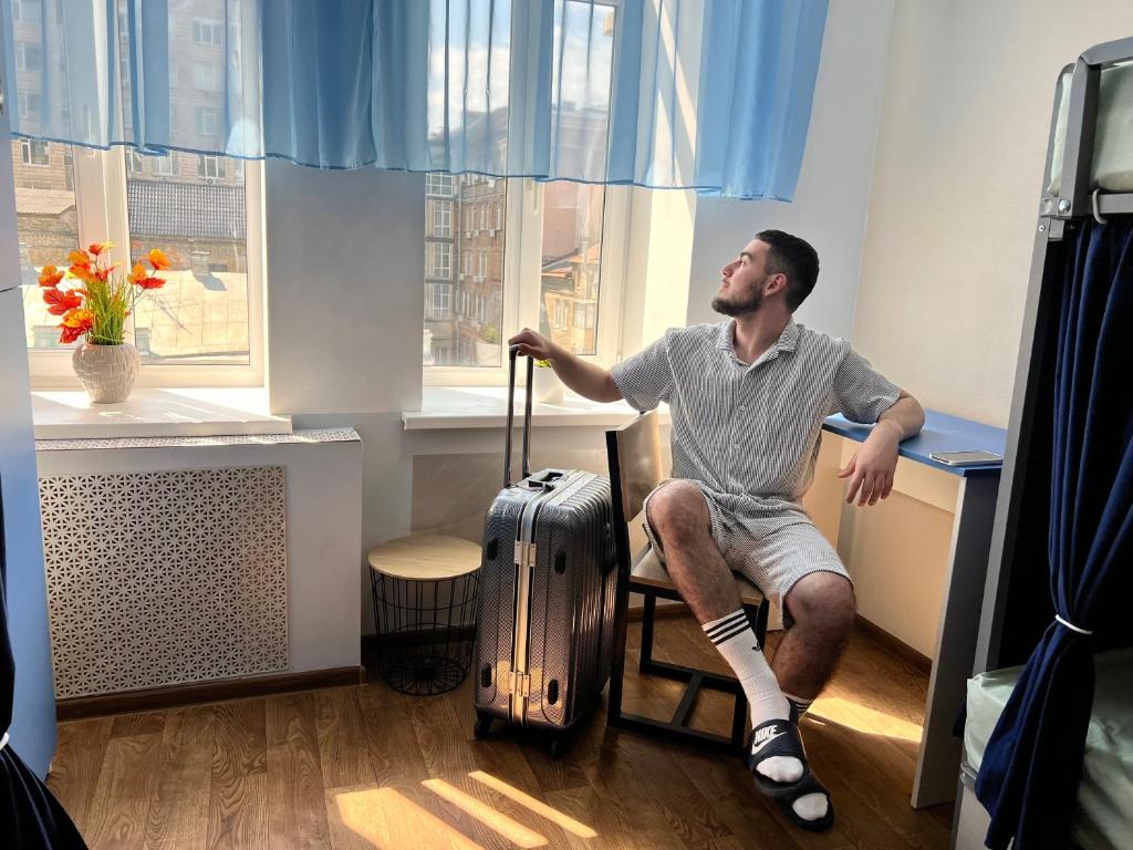un uomo seduto su una sedia con una valigia di Hostel on Universytet a Kiev