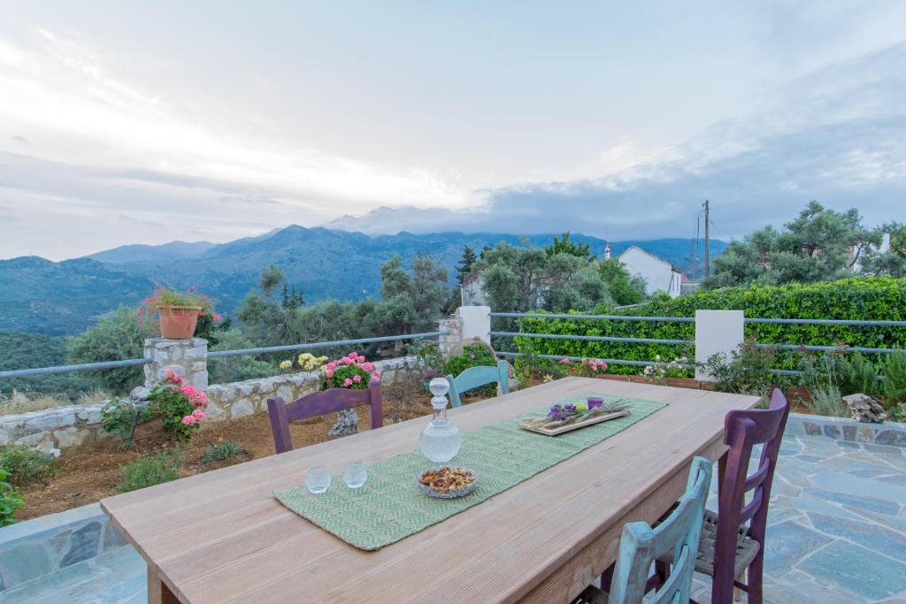a wooden table on a patio with mountains in the background at Ortaki Traditional House in Loúlos