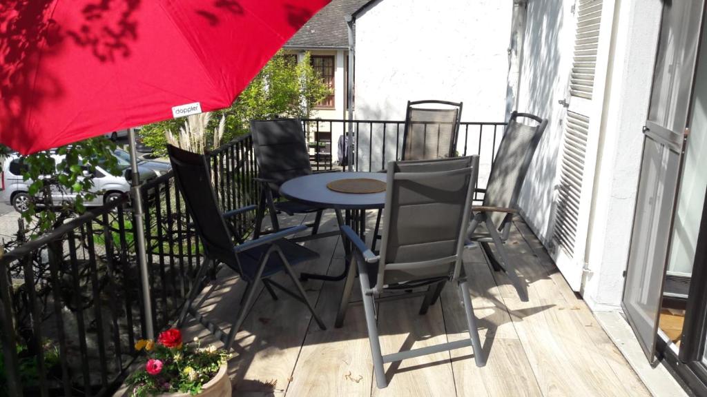 d'une terrasse avec une table, des chaises et un parasol rouge. dans l'établissement Große Ferienwohnung in Koblenz, à Coblence