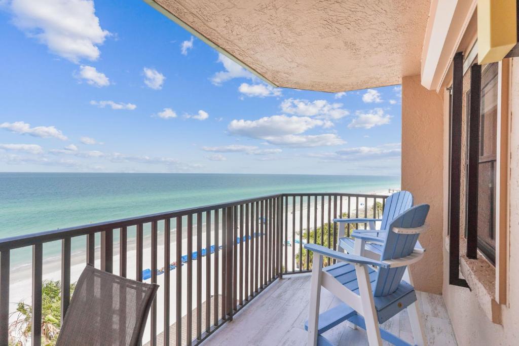 a balcony with two blue chairs and the ocean at Emerald Isle 604 in St. Pete Beach