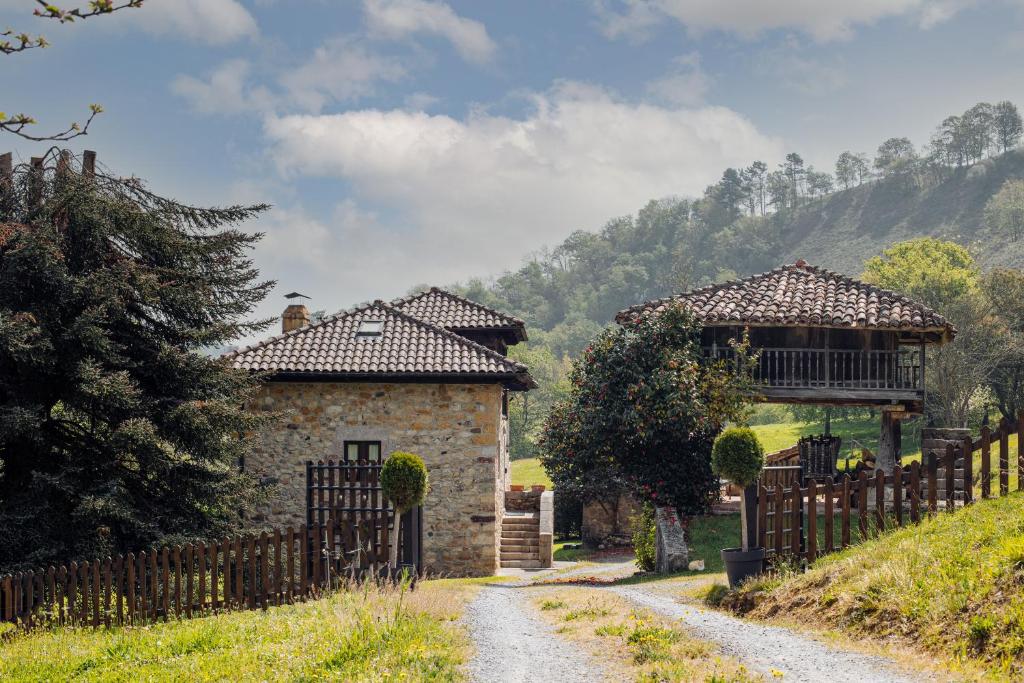 a stone house with a gate and a gazebo at Finca La Casería LA CASA in Cangas de Onís