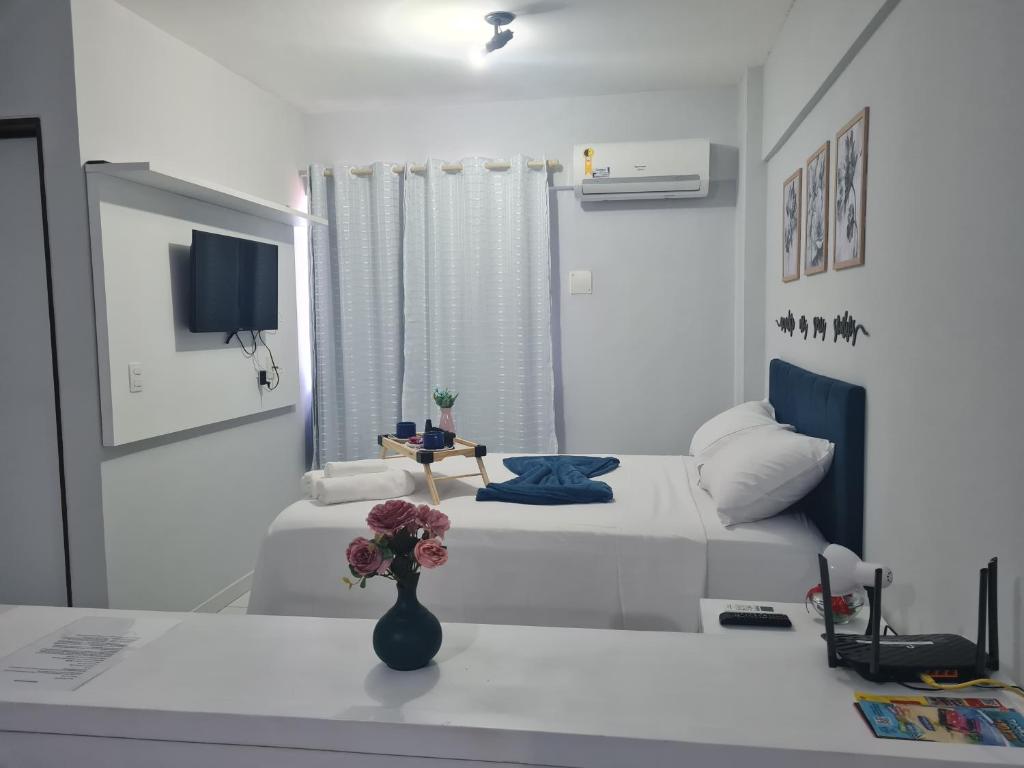 a white room with two beds and a vase with flowers at Manaíra Flat 206 Em frente ao shopping Manaíra in João Pessoa