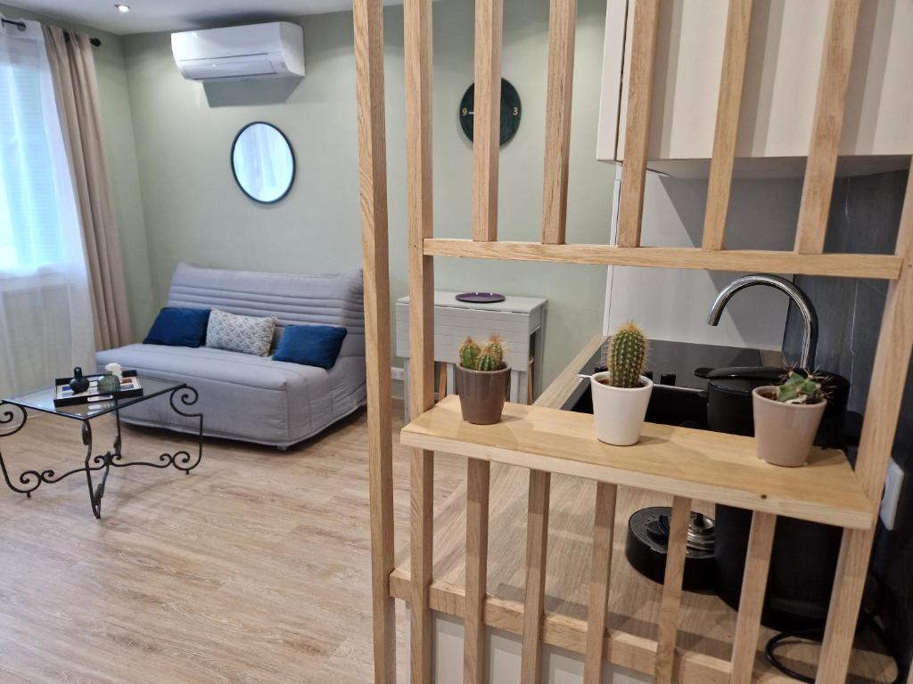 een woonkamer met een bank en een plank met planten bij T2 Cosy proche centre ville avec parking gratuit in Ajaccio