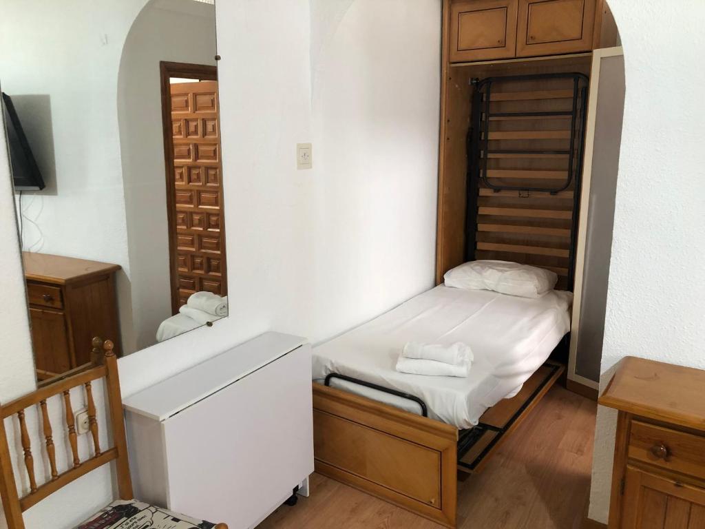 a small bedroom with a bed and a mirror at San Isidro Labrador, apartamento en Las Vistillas junto a metro Puerta de Toledo in Madrid