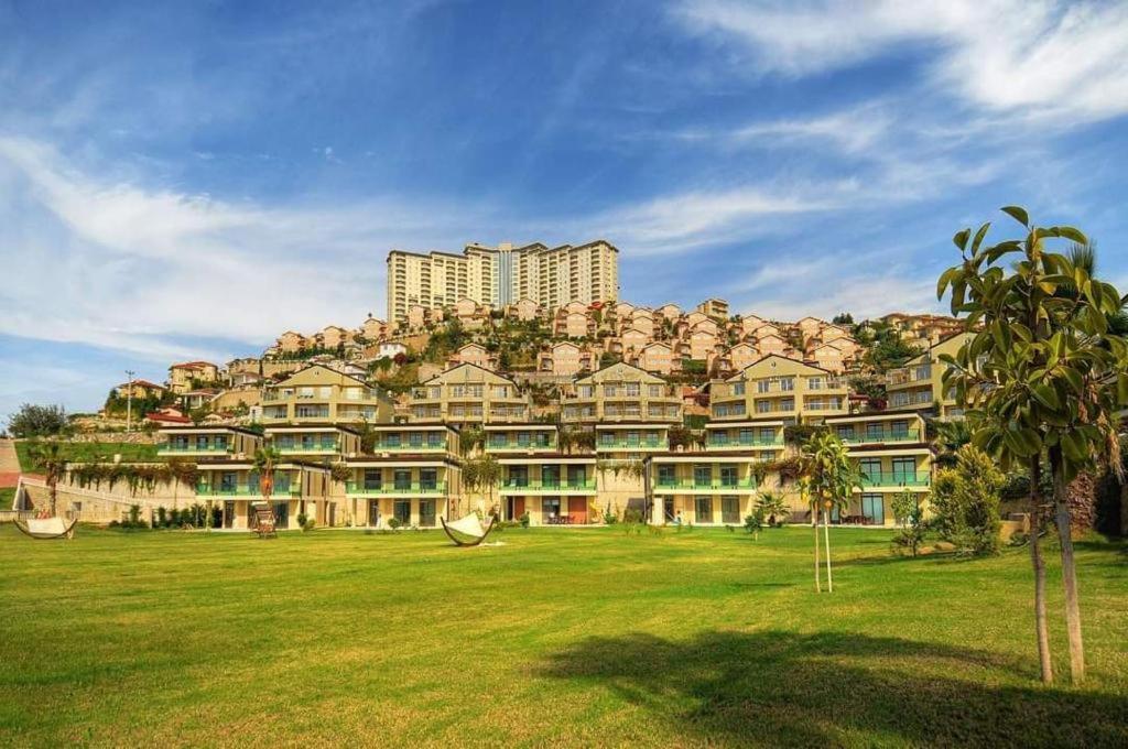 un gran edificio situado en lo alto de un exuberante campo verde en Alanya gold city hotel main building 3 bedroom apartment, en Alanya