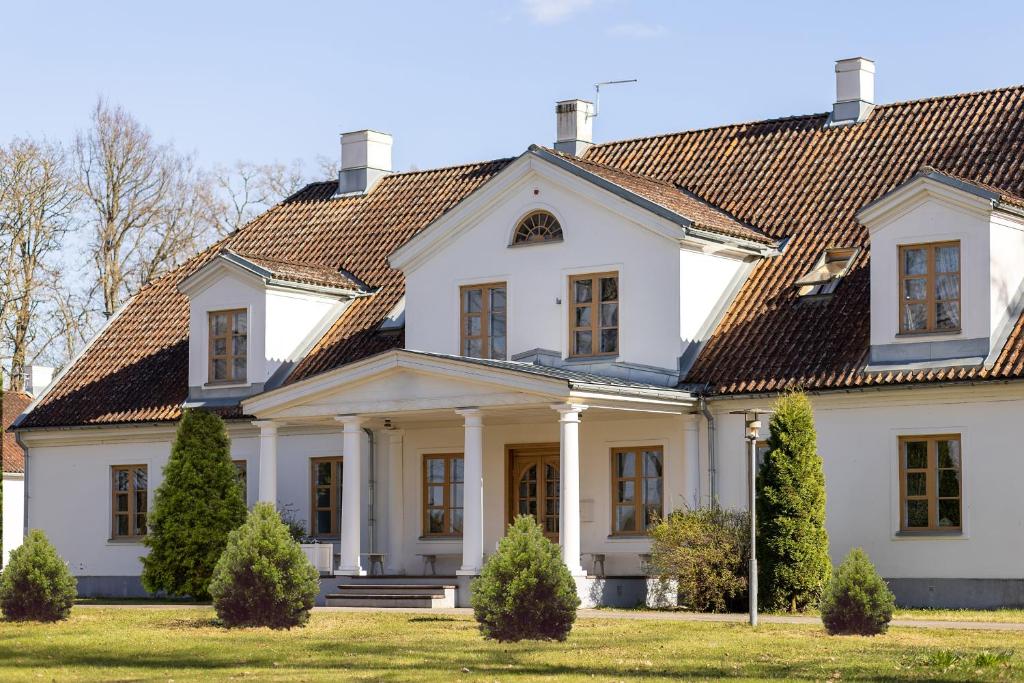 duży biały dom z dachem wyłożonym kafelkami w obiekcie Skangaļu muiža w mieście Skangaļi