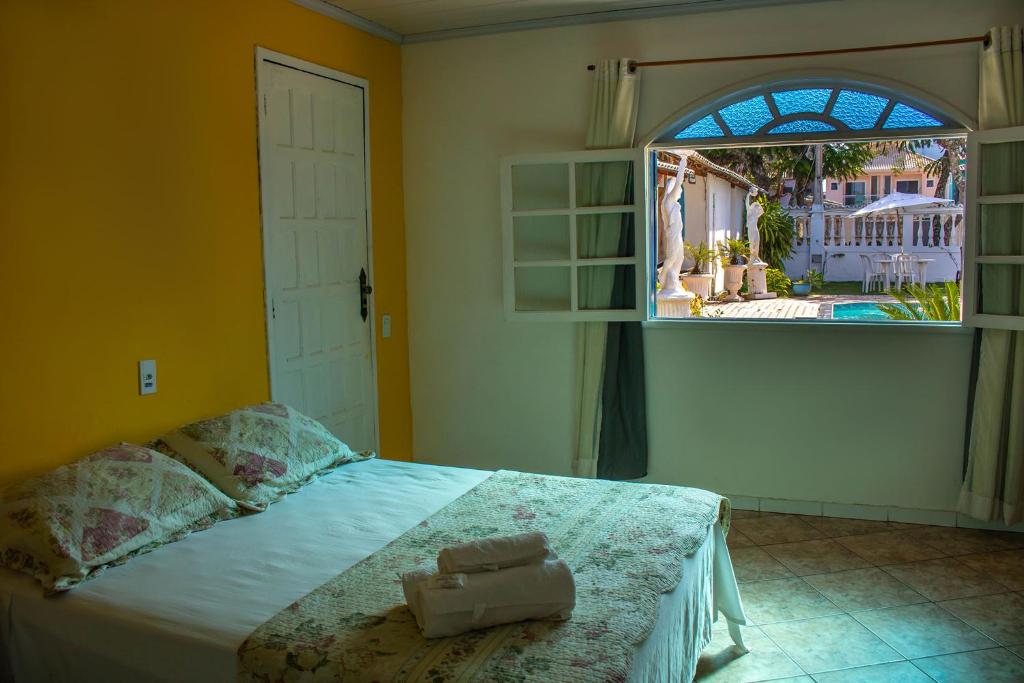 1 dormitorio con cama y ventana abierta en Pousadinha da Bia en Rio das Ostras