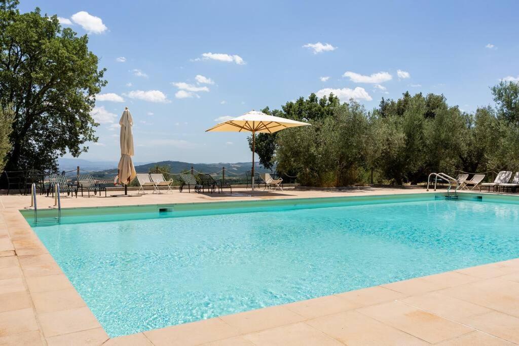 una gran piscina con sombrilla y sillas en Charming Castle, en Monte lʼAgello