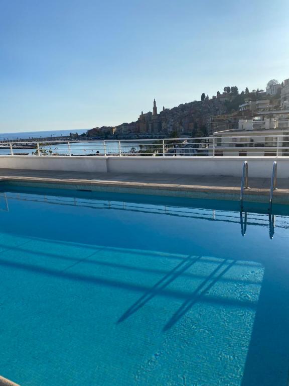 a pool of water with the shadow of a building at Rêve de sable appartement avec jardin et parking in Menton