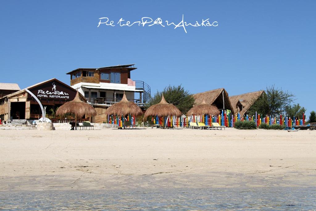a beach with straw umbrellas and chairs on the beach at Chez Peter Pan Anakao in Anakao