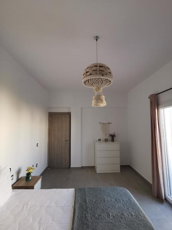 a white bedroom with a large bed and a chandelier at Mantalena's house in Antiparos