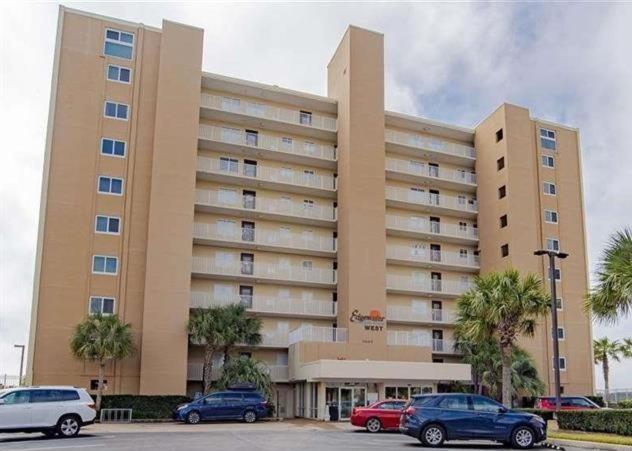 een groot gebouw met auto's geparkeerd op een parkeerplaats bij Edgewater West 53 by ALBVR - This Beachfront Condo is Perfect for your next Family Getaway in Gulf Shores