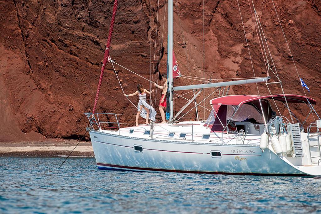 um homem parado num barco à vela na água em Orpheus em Chora, Ios