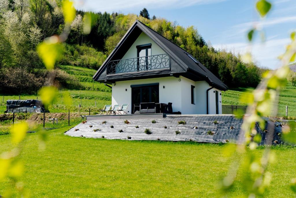 a small white house with a large wooden deck at Domek pod Nowiną in Tylmanowa