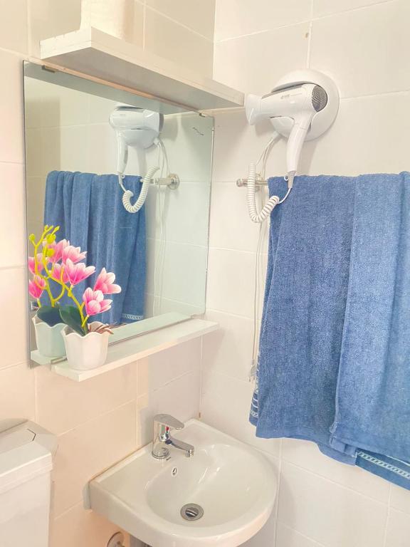 a bathroom with a sink and a mirror and a blue towel at Quarto Nº8 LUMA - Central Praia in Praia