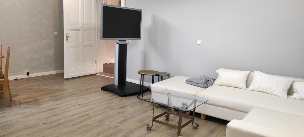 ein Wohnzimmer mit einem weißen Sofa und einem Flachbild-TV in der Unterkunft Gästewohnung Cottbuser City in Cottbus