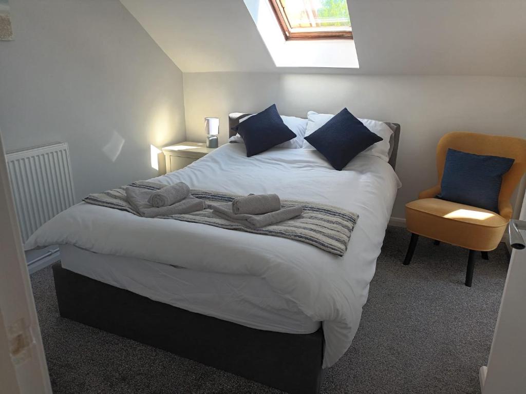 a bedroom with a large bed with blue pillows and a chair at First Floor One bedroom Apartment Quiet Location in Stafford in Stafford