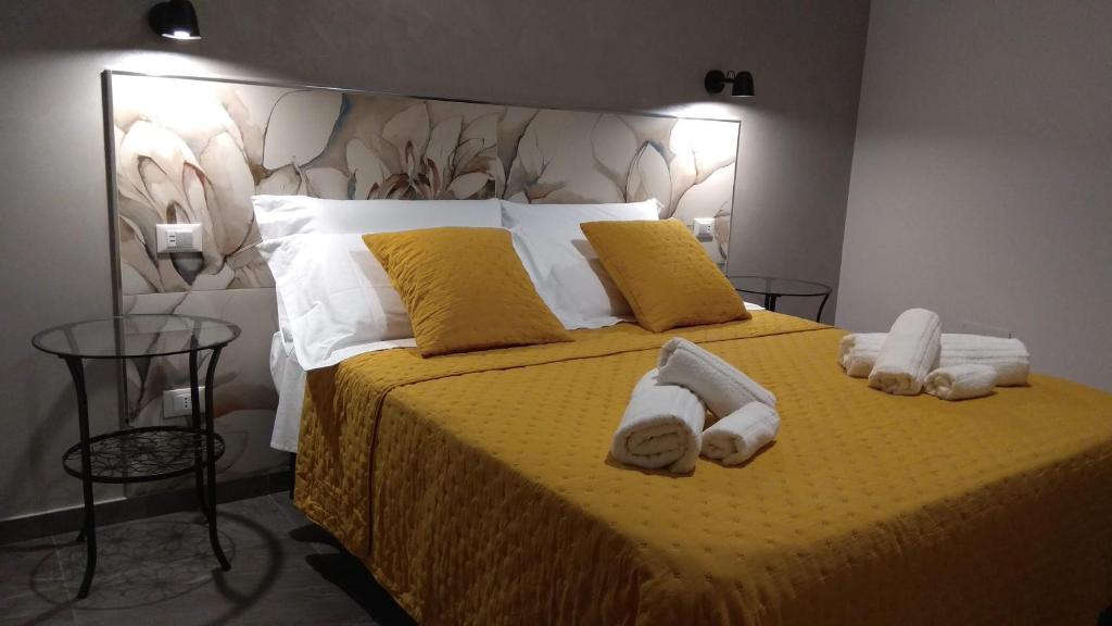 Un dormitorio con una cama amarilla con toallas. en La Casa di Elisa, en Riposto