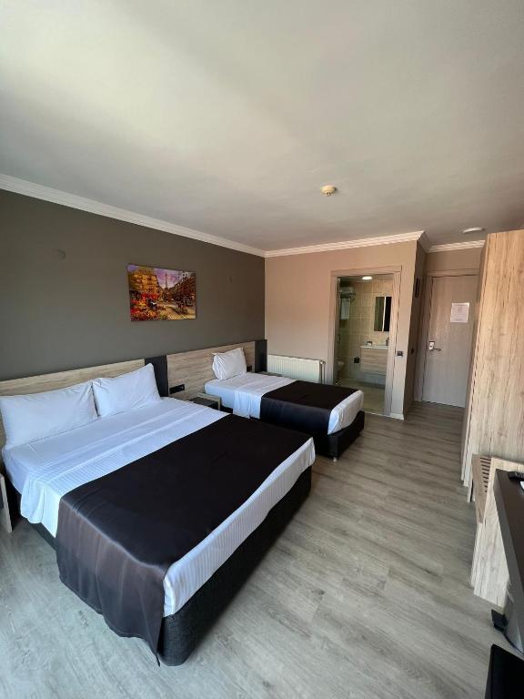 a hotel room with two beds and a television at Grand Faik Hotel in Çeşme