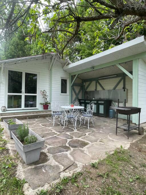un patio avec une table, des chaises et un barbecue dans l'établissement Chalet au bord de l'étang, à Sérilhac