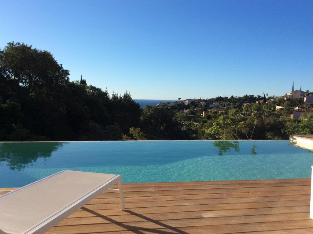 une piscine avec un banc sur une terrasse en bois dans l'établissement Magnifique villa vue mer dans le golfe de St-Tropez, à Roquebrune-sur Argens