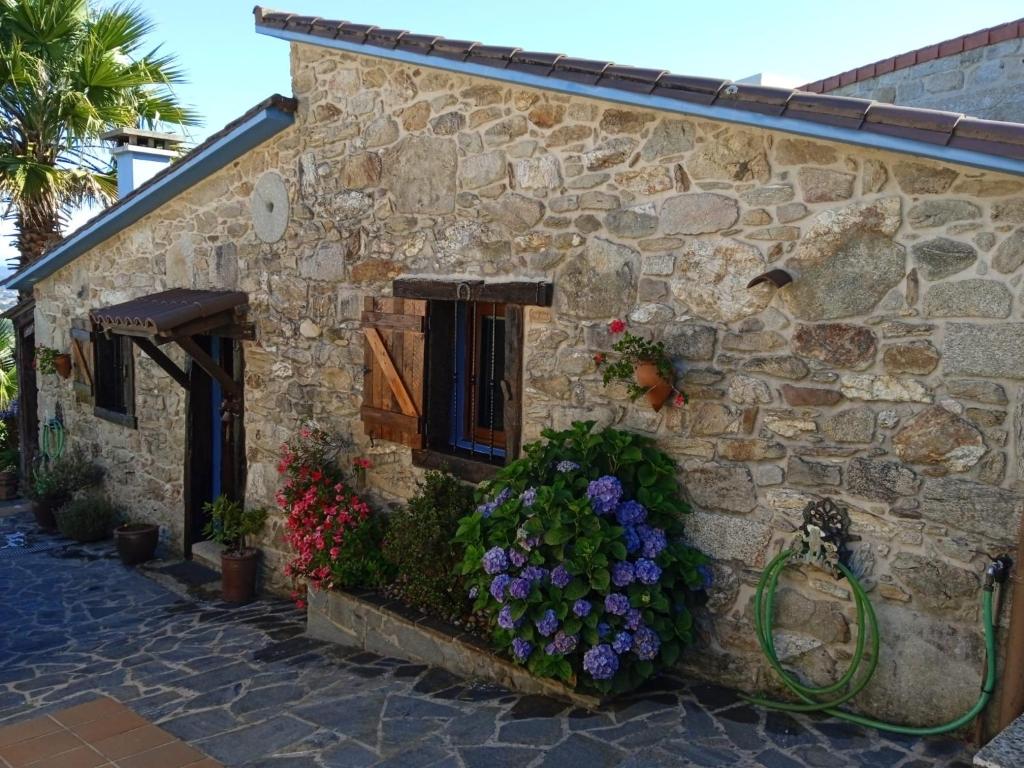 a stone house with flowers on the side of it at Casa vacacional o trisquel in Pontevedra