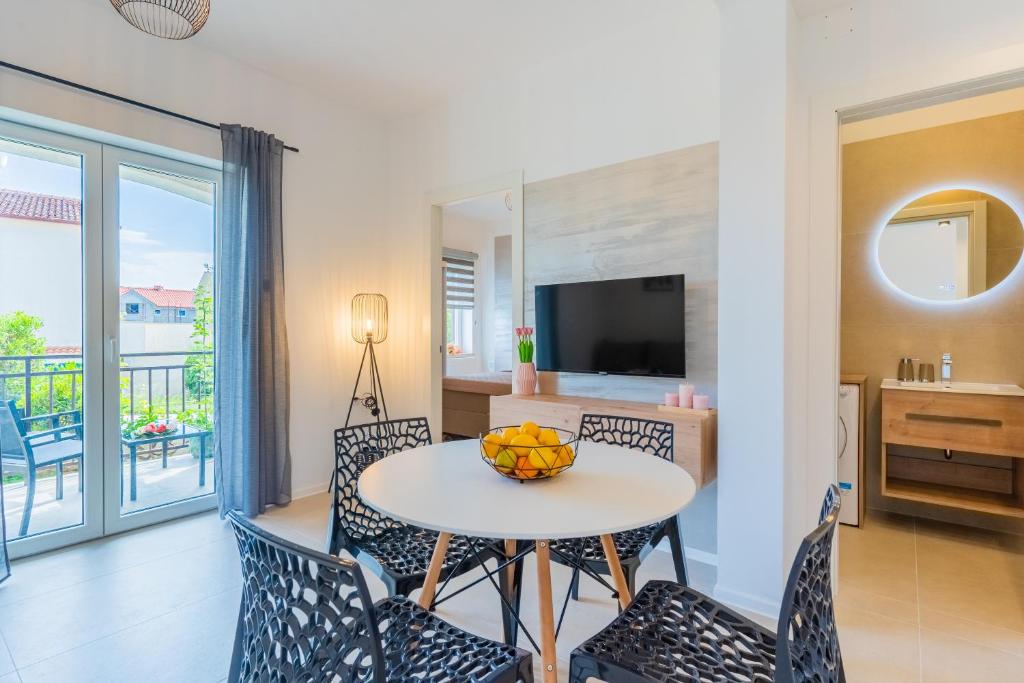 a living room with a table and chairs and a television at Apartments Ivanka Cres in Cres