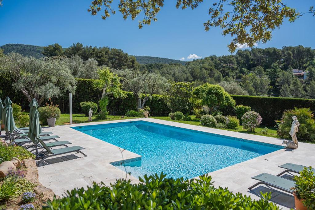 una piscina en un jardín con sillas y árboles en Le Clos Serein, en Le Beausset