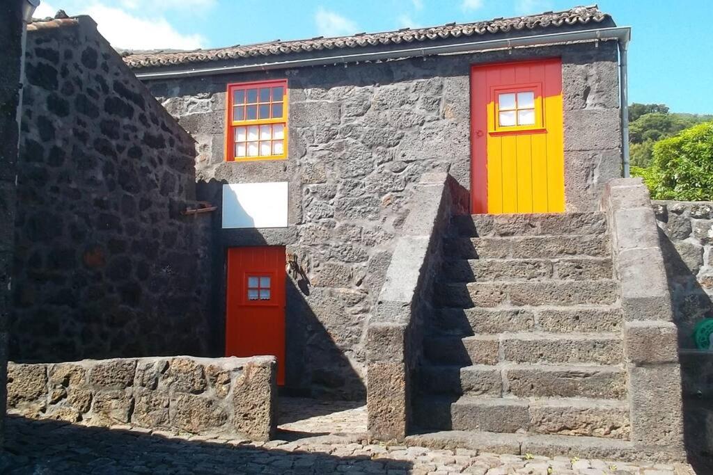 a house with red and yellow doors and stairs at Casas da Figueira in São Roque do Pico